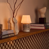 Tafellamp oplaadbaar Hooch Large in silver travertine op een houten plank naast boeken en een keramische vaas