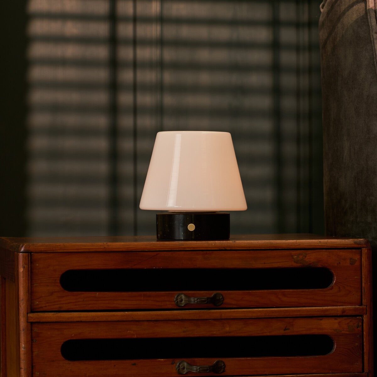 Oplaadbare tafellamp Hooch Small Nero Marquina Marble brandend op een dressoir voor gestreepte lamellen