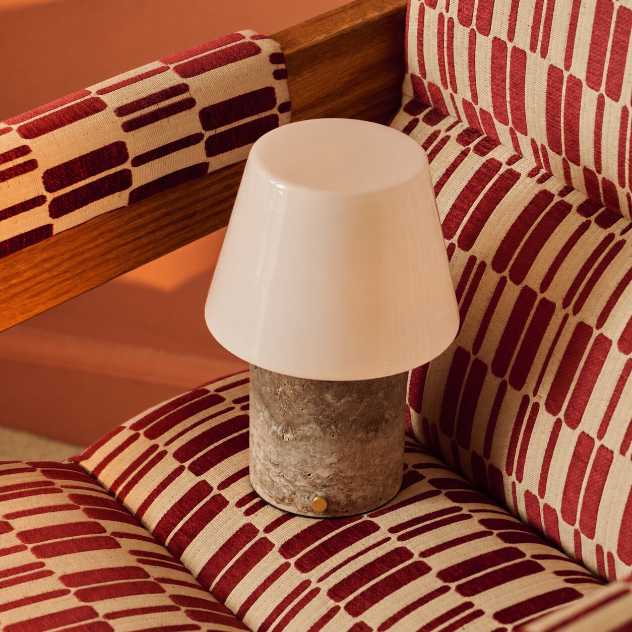 Tafellamp oplaadbaar Hooch met Silver Travertine voet op een rood-wit gestreepte fauteuil