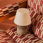 Tafellamp oplaadbaar Hooch met Silver Travertine voet op een rood-wit gestreepte fauteuil