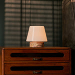 Tafellamp oplaadbaar Hooch Small in roze marmer, zacht brandend op een vintage houten dressoir in de avond