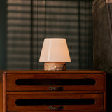 Tafellamp oplaadbaar Hooch Small in roze marmer, zacht brandend op een vintage houten dressoir in de avond