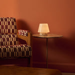 Tafellamp oplaadbaar Hooch Small in Rosa Aurora marmer op een rond bijzettafeltje naast een fauteuil