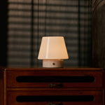 Oplaadbare tafellamp Hooch Small in Rosa Aurora marmer, warm licht op een donker houten kastje