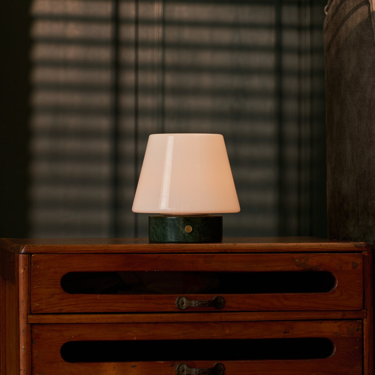 Oplaadbare tafellamp Hooch Small Verde Alpi Marble brandend op een dressoir voor gestreepte lamellen
