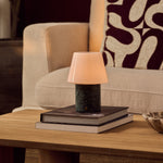 Hooch Green rechargeable table lamp with tapered glass shade and marble base resting on stacked books