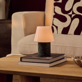 Hooch Green rechargeable table lamp with tapered glass shade and marble base resting on stacked books