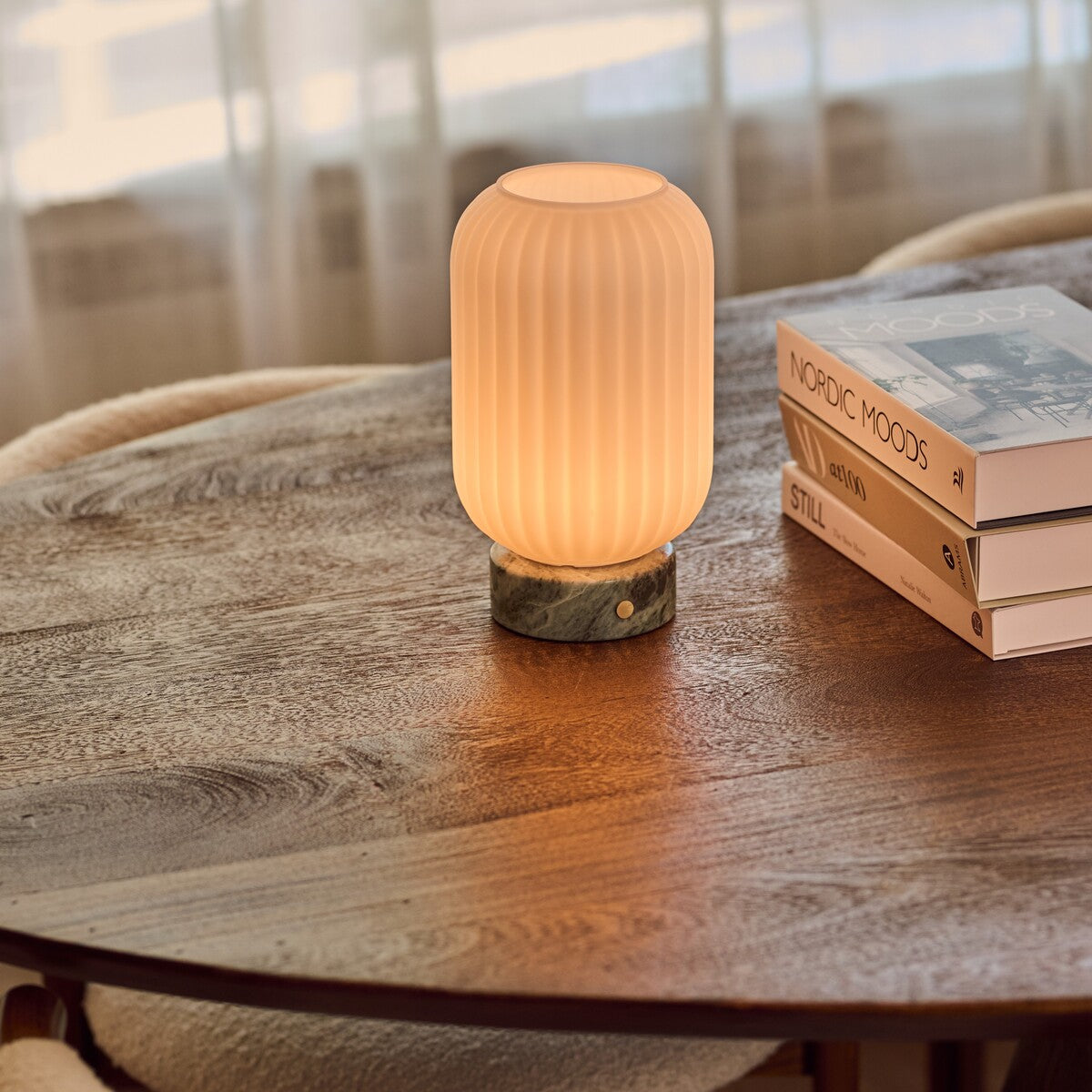 Tafellamp oplaadbaar Kota Ice Green marmer, zacht brandend op een houten consoletafel in avondsfeer