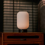 Tafellamp oplaadbaar Kota met geribbeld glazen kapje op een vintage dressoir bij een gestreepte fauteuil