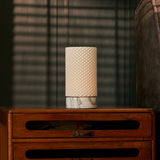 Oplaadbare tafellamp Luna in Arabescato marmer en porselein op een vintage houten ladekast met gestreepte schaduwen.