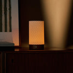 Tavellio tafellamp oplaadbaar Luna Chestnut, brandend op donker houten kast naast gestreepte kunst