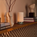 Oplaadbare tafellamp Luna naast sculpturale keramische vazen en een boek op een geblokt houten dressoir
