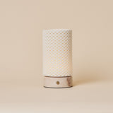 Oplaadbare tafellamp Luna in Rosa Aurora marmer en porselein, studiofoto tegen een beige achtergrond.