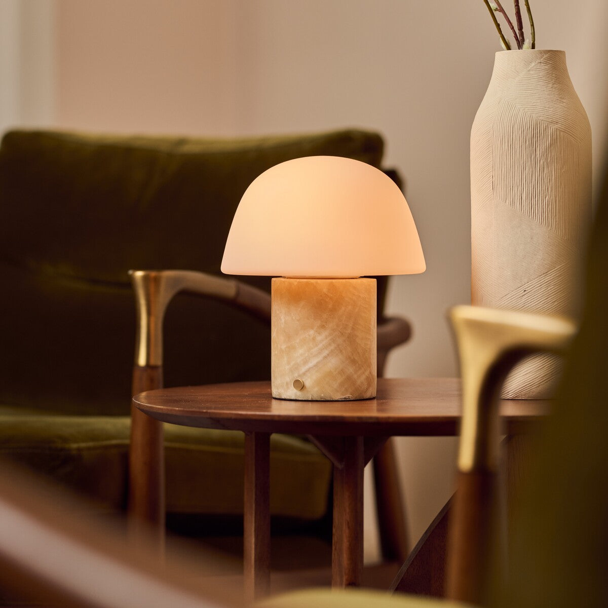 Tafellamp oplaadbaar Maes Honey Onyx marmer op een bijzettafel tussen een olijfgroene fauteuil en keramische vaas