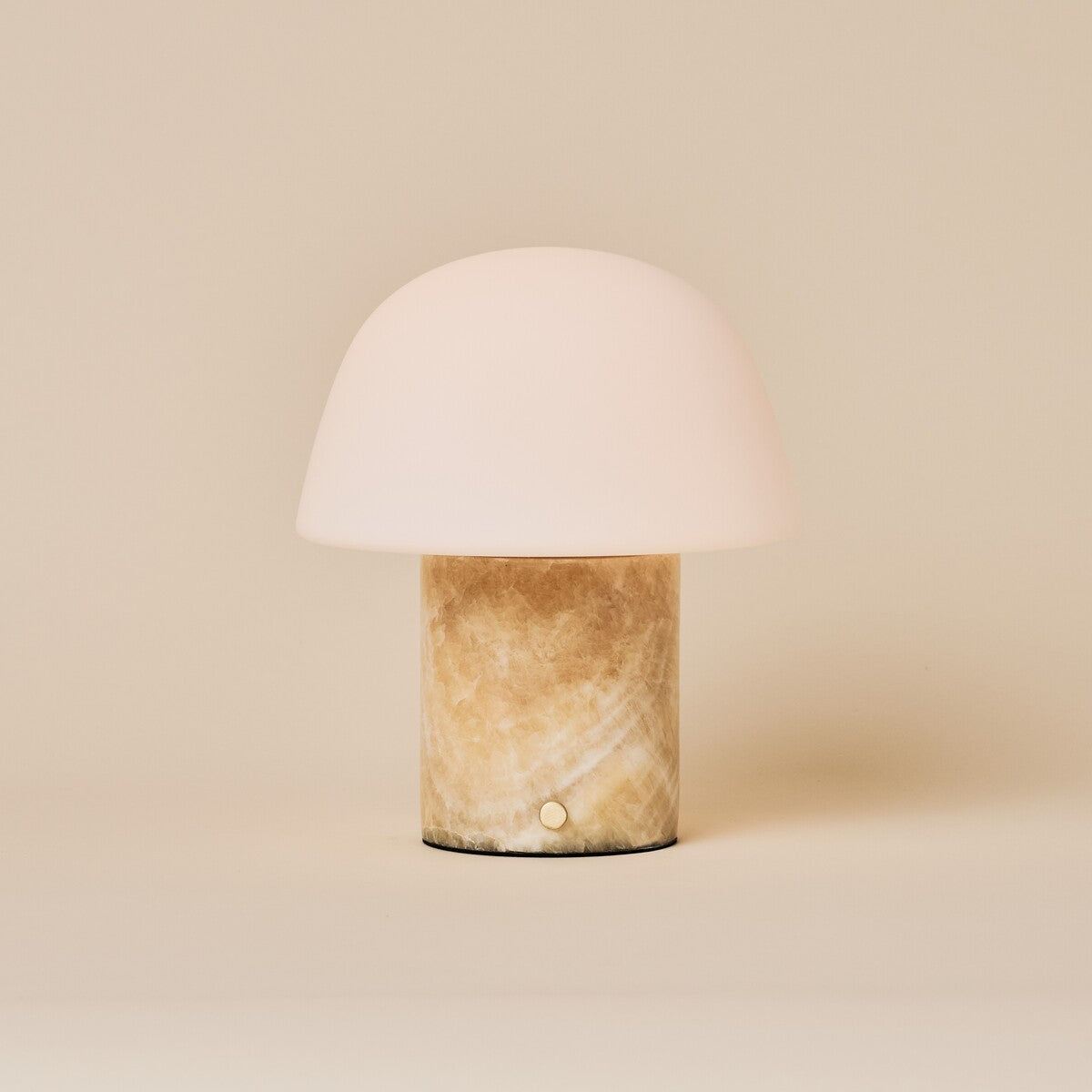 Oplaadbare tafellamp Maes Honey Onyx marmer met melkglazen bolkap op een crème studioachtergrond