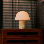 Tavellio tafellamp oplaadbaar Maes Honey Onyx marmer gloeiend op een ladekast met lamellen-schaduw op de muur