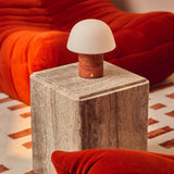 Oplaadbare tafellamp Maes Red Travertine op een marmeren bijzettafel tussen roodoranje fluwelen fauteuils