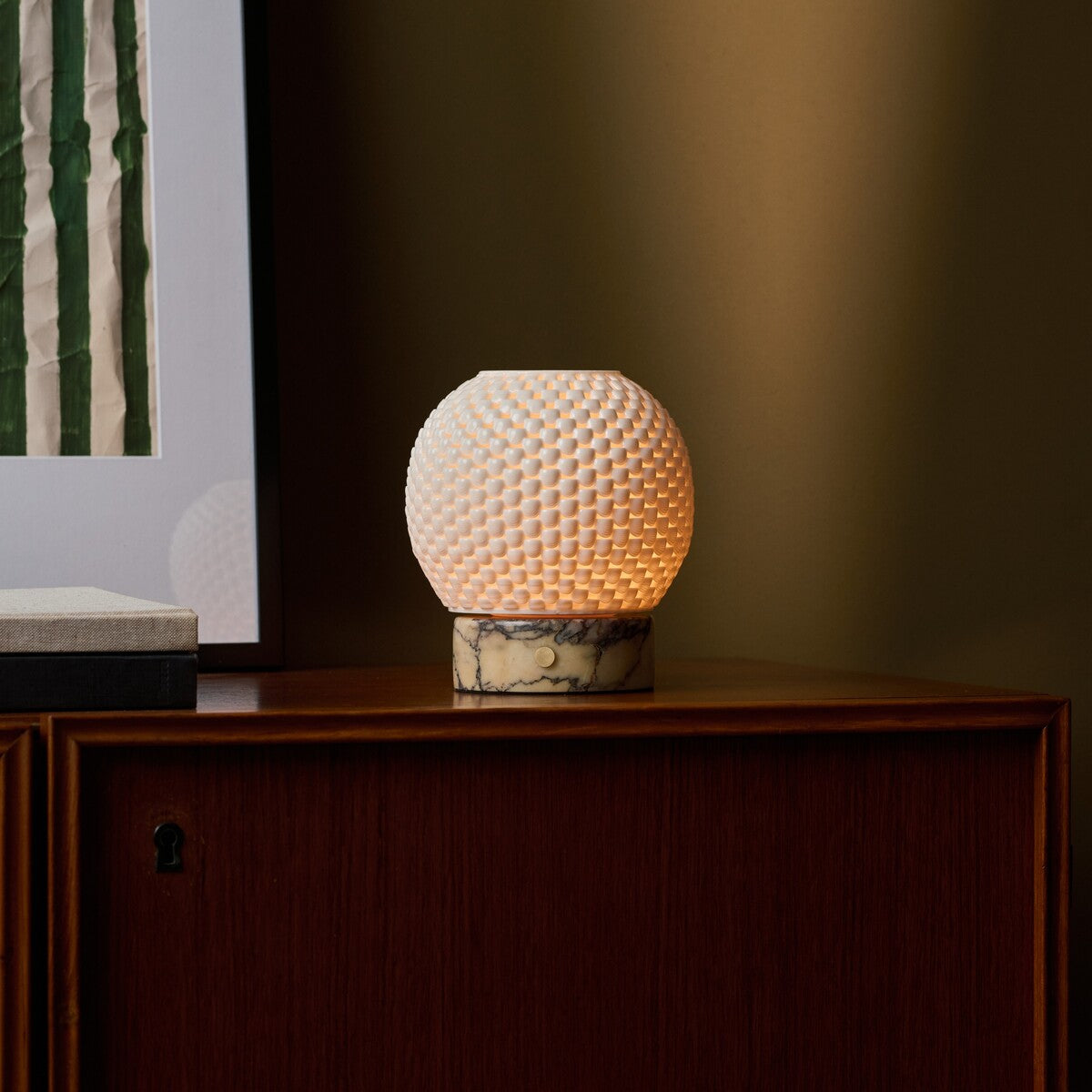 Mare cordless table lamp beside framed wall art on a dark wood cabinet