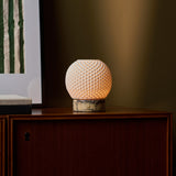 Mare cordless table lamp beside framed wall art on a dark wood cabinet
