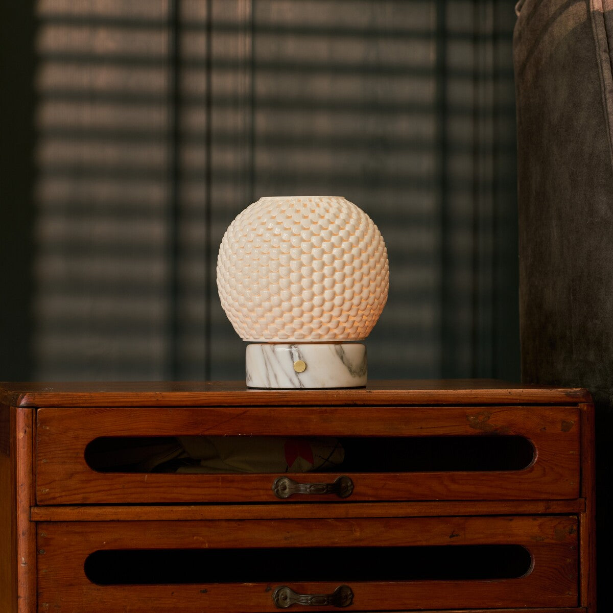 Oplaadbare tafellamp Mare met marmeren voet met donkere adering op een houten dressoir bij jaloezieën