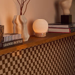 Mare rechargeable table lamp with pink marble base styled on a shelf beside ceramic vases and books