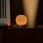 Cordless table lamp featuring a dimpled porcelain globe shade glowing above a pink marble base