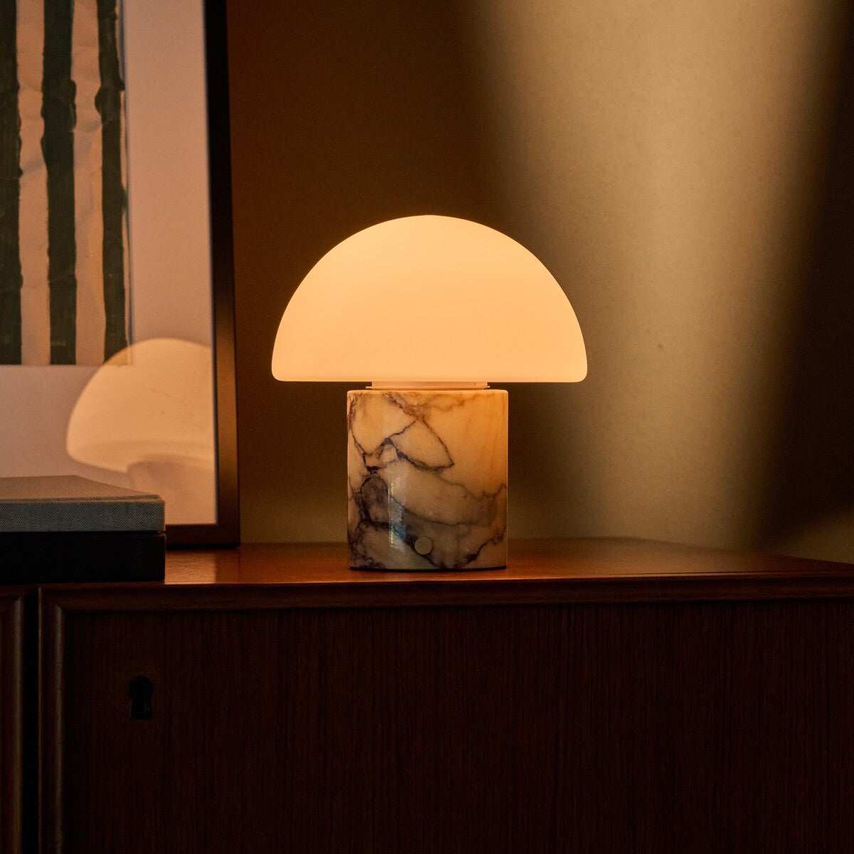 Mare rechargeable table lamp with golden Calacatta Vionaro marble base on a wood cabinet