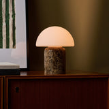 Oplaadbare tafellamp Maris Large gloeiend op een dressoir tegen een olijfgroene wand