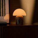 Oplaadbare tafellamp Maris Large gloeit bij schemering op een donker houten dressoir