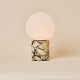 Calacatta Vionaro marble cordless table lamp with round glass globe shade on a beige backdrop