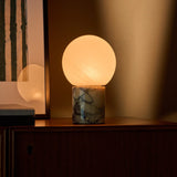 Cordless table lamp in Calacatta Vionaro marble with glass globe shade on a walnut console table