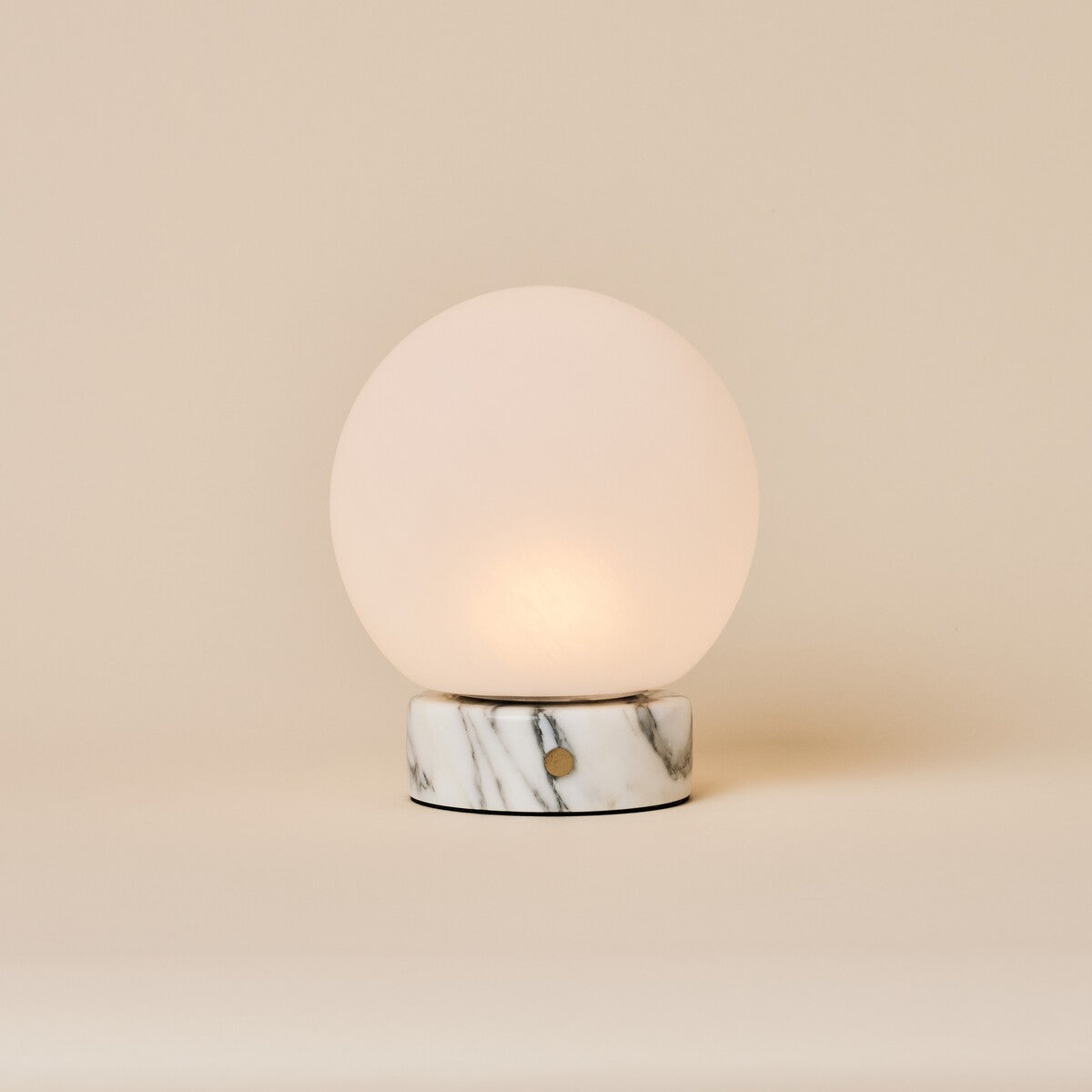 Oplaadbare tafellamp Metsu Small Arabescato wit marmer met glazen bol op beige achtergrond
