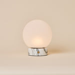 Oplaadbare tafellamp Metsu Small Arabescato wit marmer met glazen bol op beige achtergrond