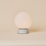 Oplaadbare tafellamp Metsu witte marmeren voet en ronde opaline bolkap op neutrale achtergrond