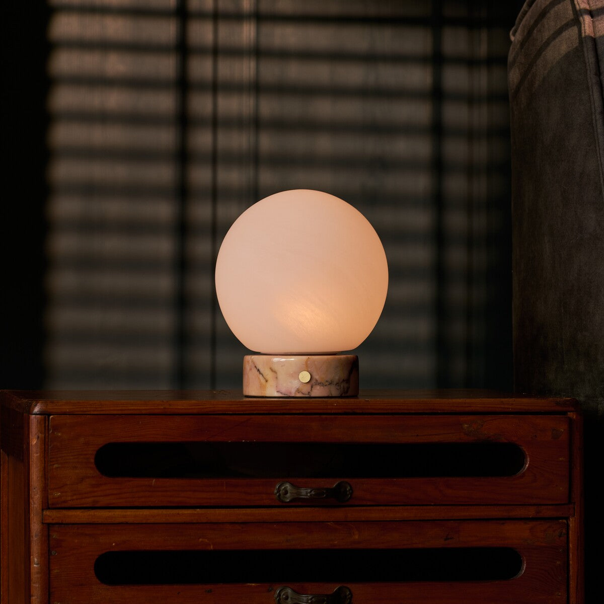 Cordless table lamp Metsu Small with Calacatta Vionaro pink marble base beside a picture frame
