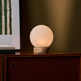 Rechargeable table lamp Metsu Small Calacatta Vionaro pink marble on a dark wood cabinet