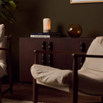 Oplaadbare tafellamp Noé Silver Travertine op boekenstapel naast amberkleurige glazen vaas