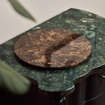 Emperador Dark marble tray resting on a scalloped green marble table beside a plant