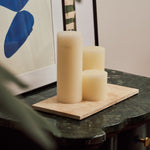 Nori medium Classic Travertine tray in beige stone holding three ivory pillar candles