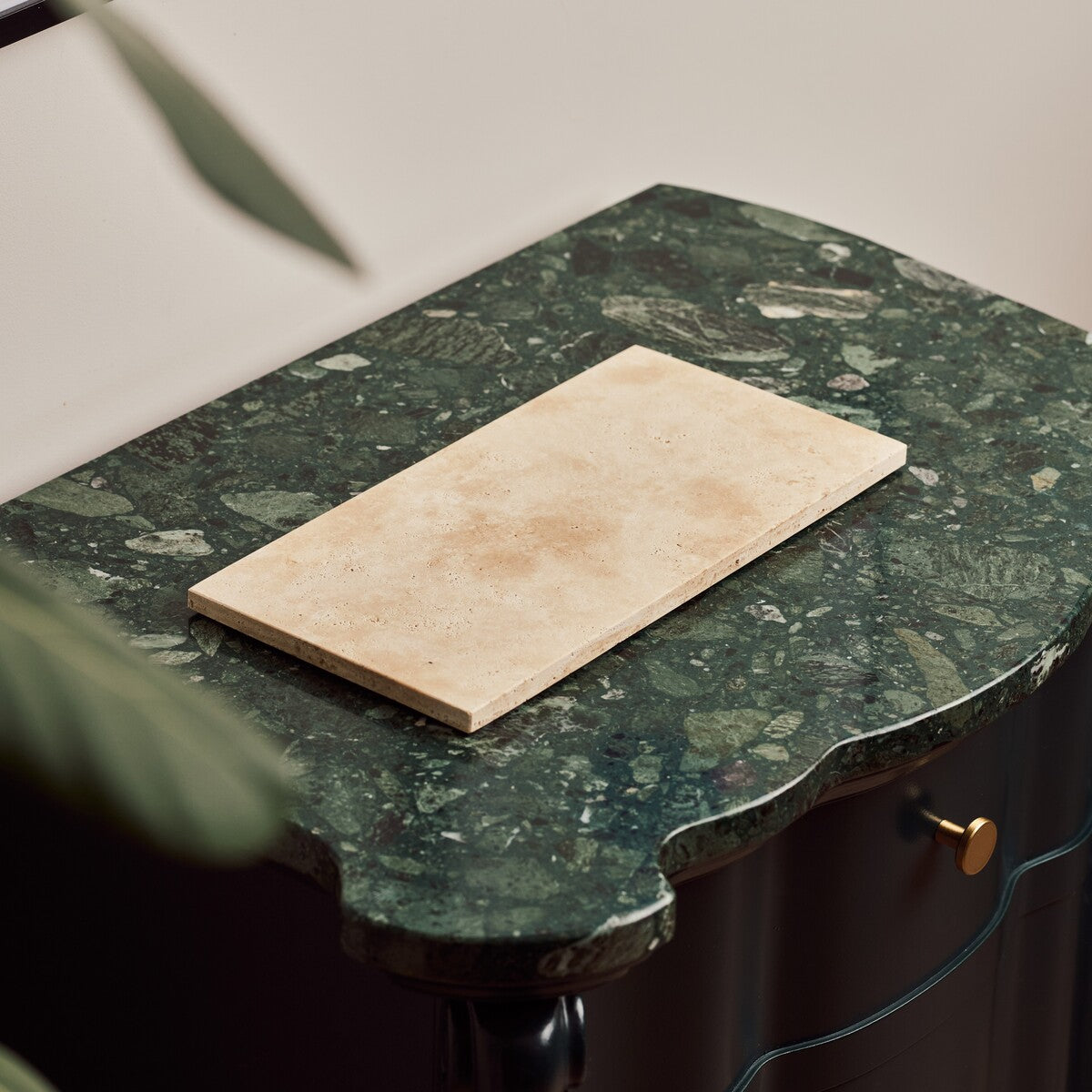 Nori medium Classic Travertine tray in light beige stone on a green marble console table