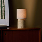 Onoda Large oplaadbare tafellamp in Classic Travertine naast een schilderij op houten kast