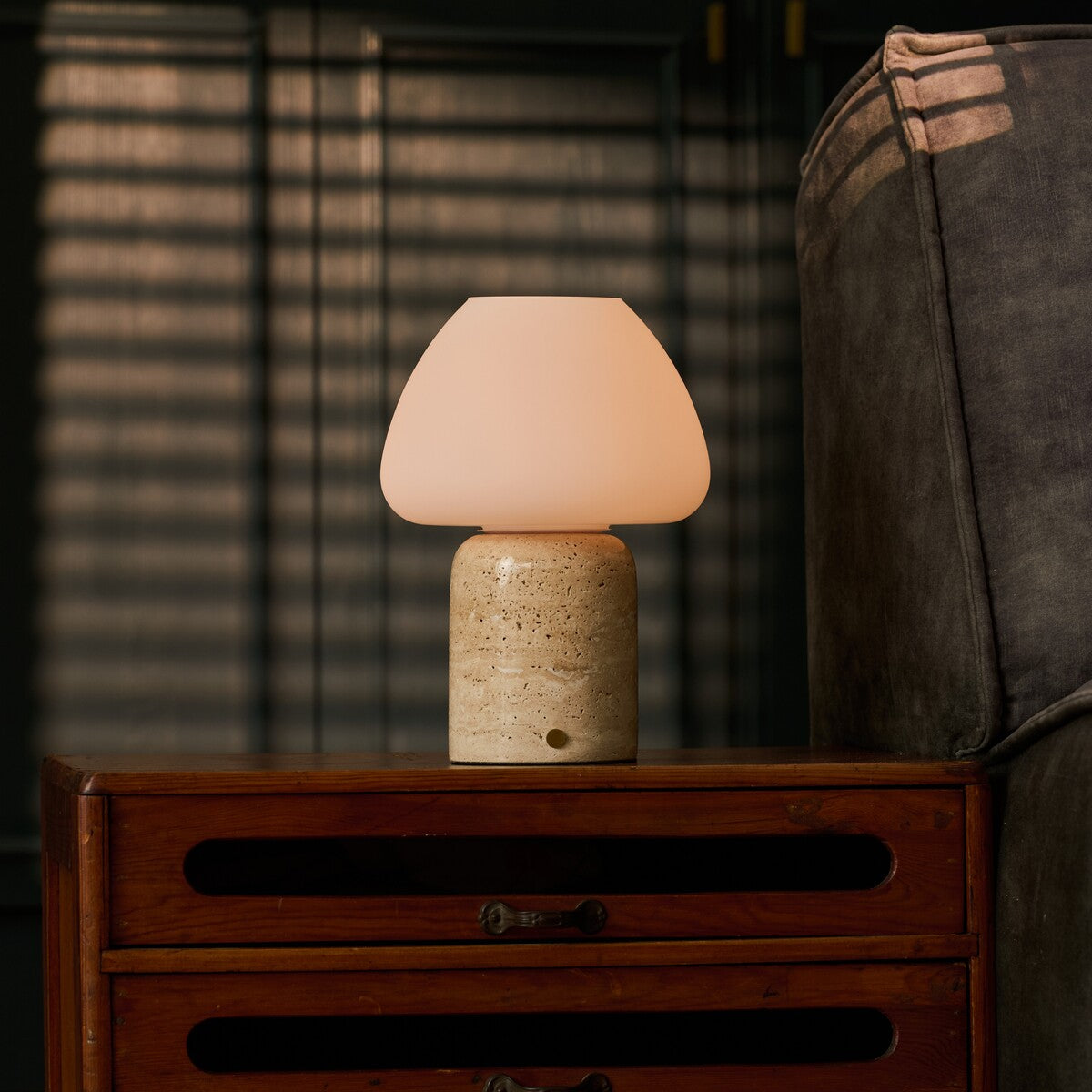 Tafellamp oplaadbaar Ostade, beige travertin op een nachtkastje bij houten lamellen