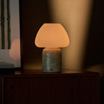 Tafellamp oplaadbaar Ostade, beige travertin voet met witte glazen kap op een houten dressoir