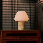 Oplaadbare tafellamp Ostade Medium in Honey Onyx marmer op houten ladekast met jaloezie-schaduw