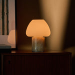 Oplaadbare tafellamp Ostade Medium in Honey Onyx marmer op donker houten dressoir naast kunstprint