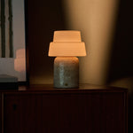 Oplaadbare tafellamp Pissarro Large Classic Travertine, beige marmeren voet, brandend op houten dressoir