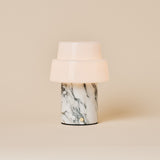 Cordless table lamp with two-tier opal glass shade and beige marble base under warm spotlight