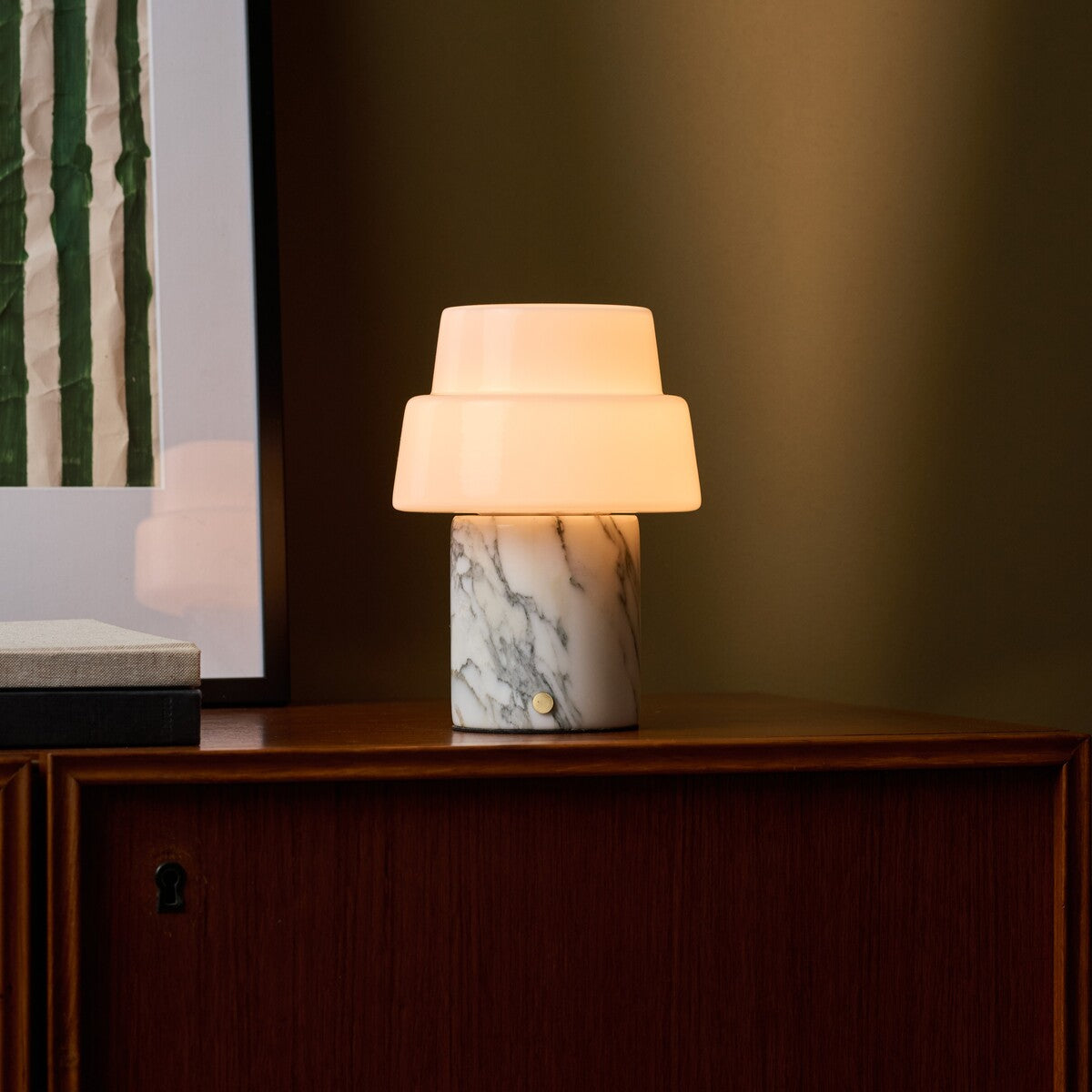 Cordless table lamp with opal glass dome shade and dark stone base beside bedroom blinds