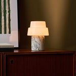 Cordless table lamp with opal glass dome shade and dark stone base beside bedroom blinds
