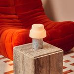 Cordless table lamp Pissarro in blue calcite marble glowing on a dark wood sideboard